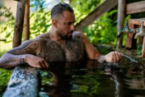 handsome tattooed man in bath in nature