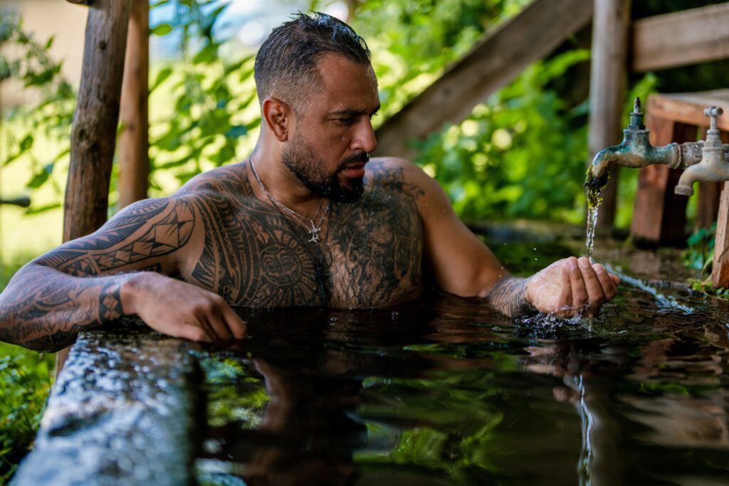 handsome tattooed man in bath in nature